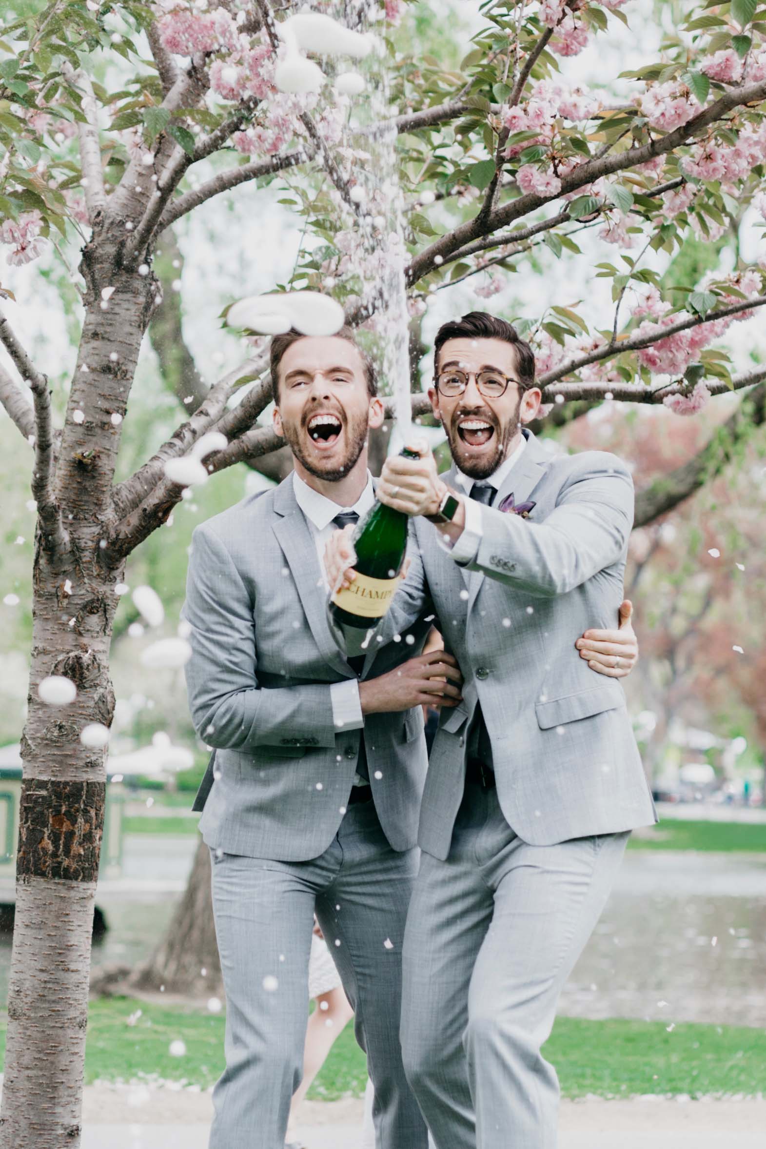 two men in suits popping a bottle of champagne