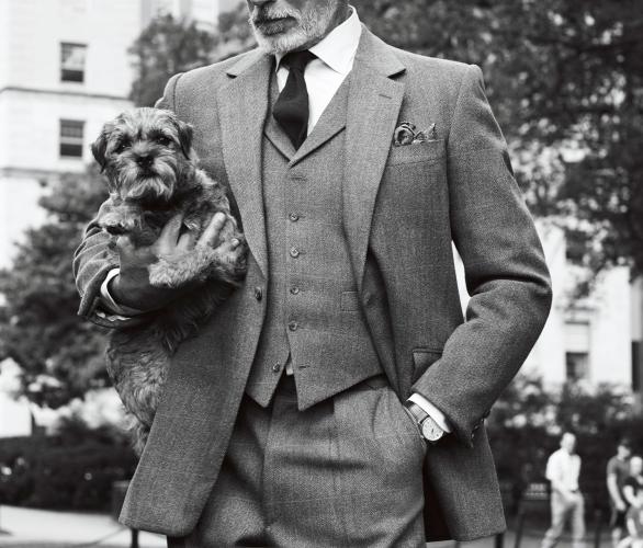 Man in a suit posing with his dog in front of The Newbury.