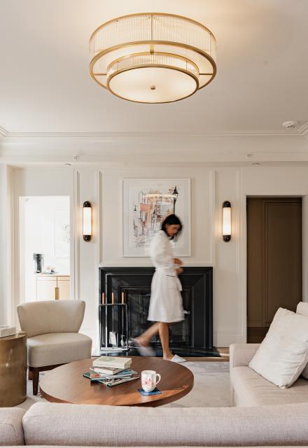 woman in robe and slippers walking in front of a fire place in hotel room 