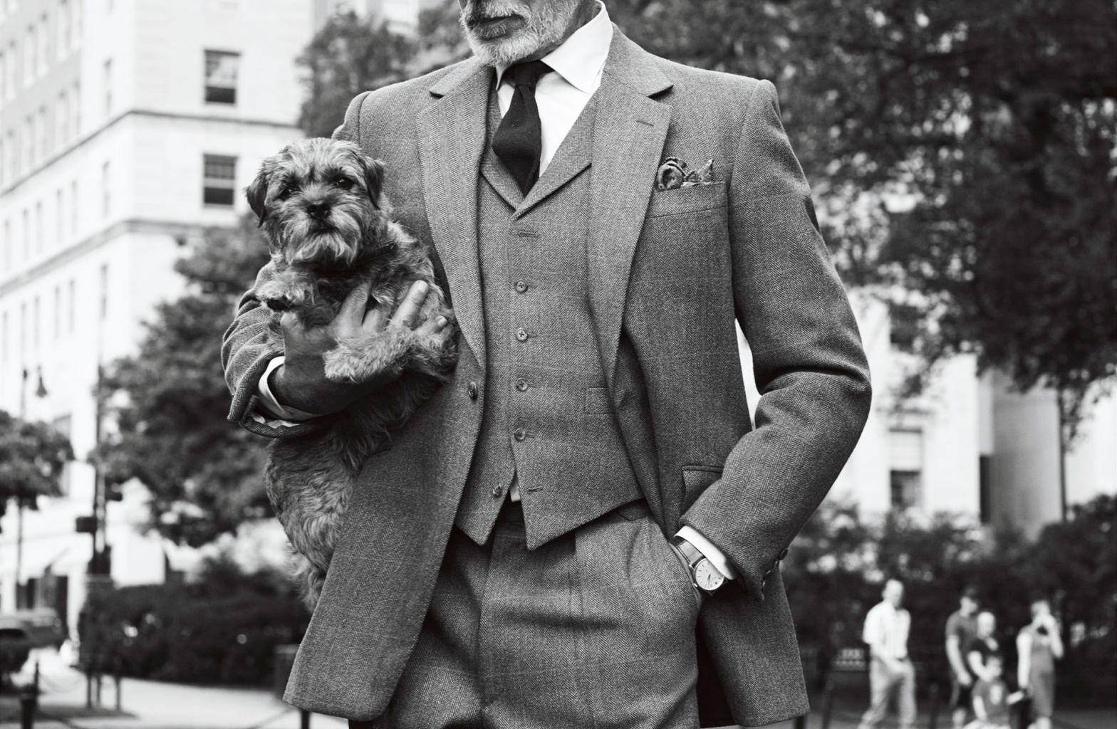Man in a suit posing with his dog in front of The Newbury.