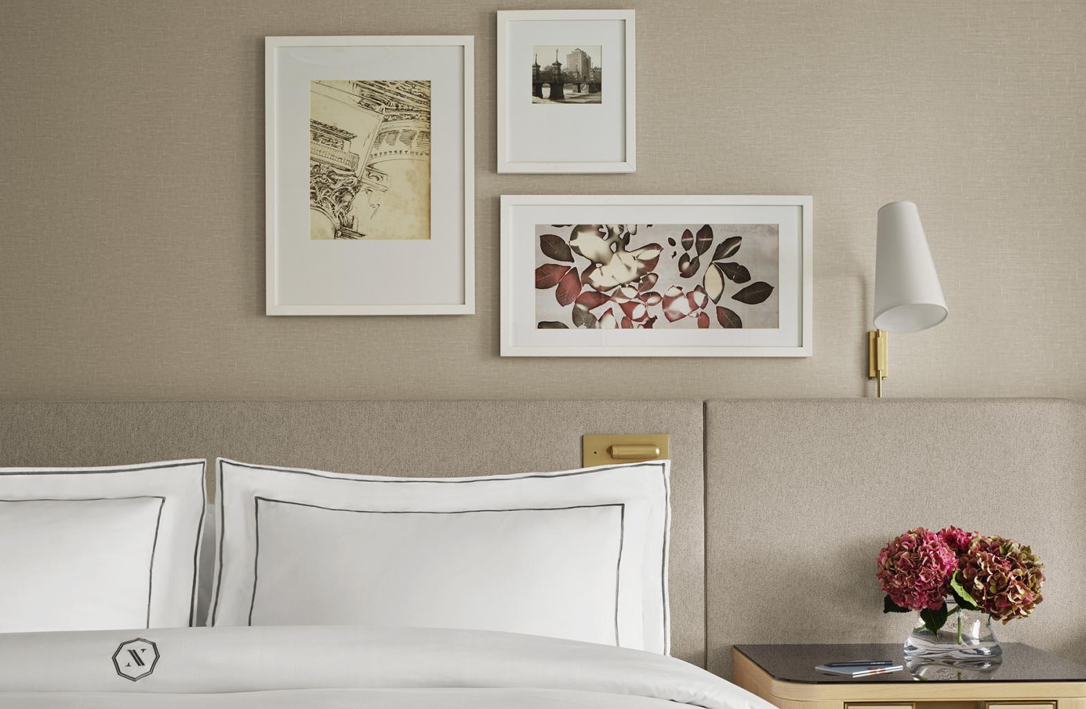 close up on bed with flowers on table and framed photos on wall