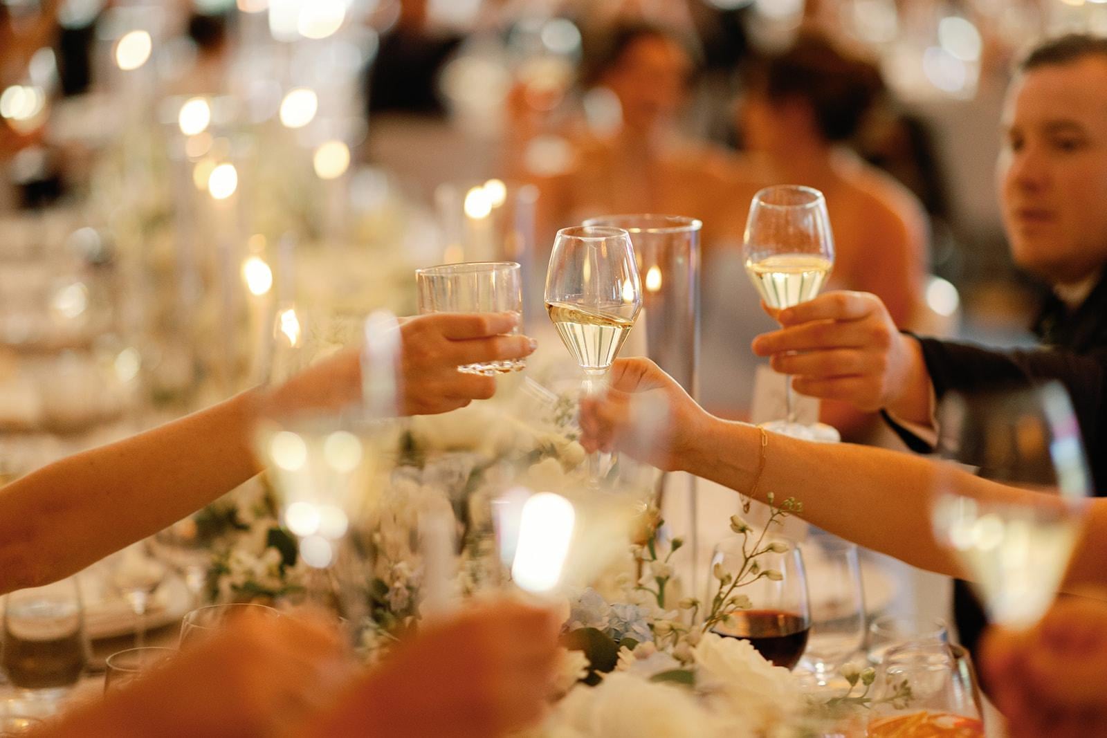 Group of people clinking champagne glasses together at wedding 