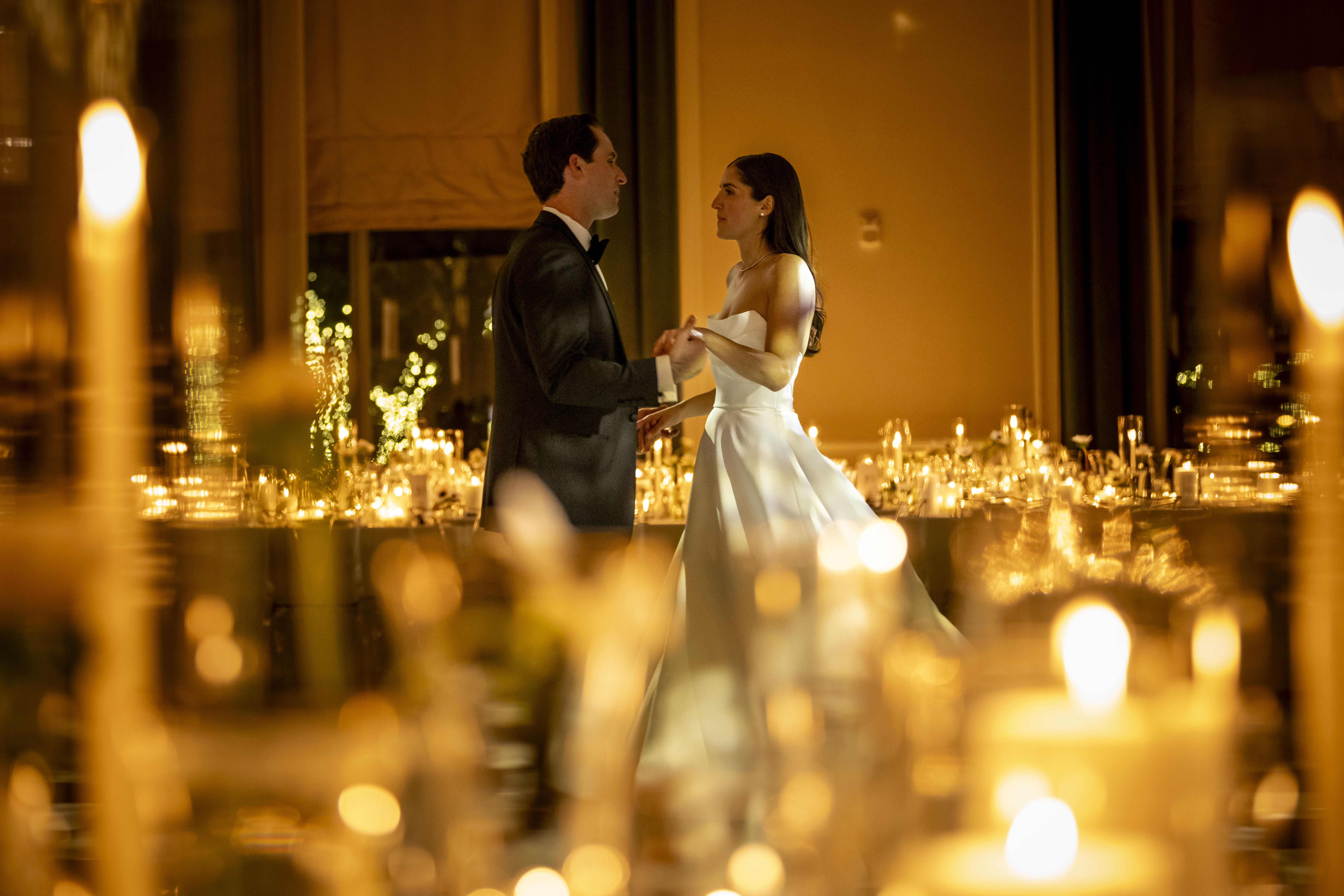 Bride and groom sharing first dance with candles surrounding them 