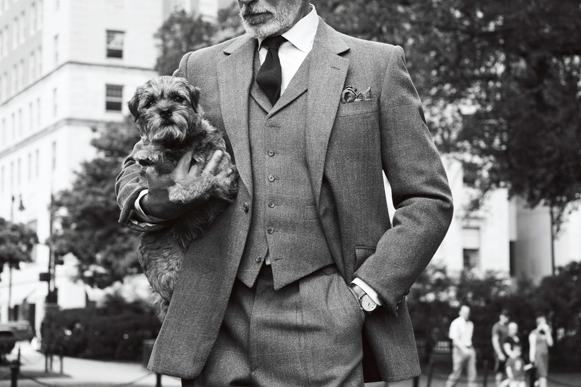 Man in a suit posing with his dog in front of The Newbury.