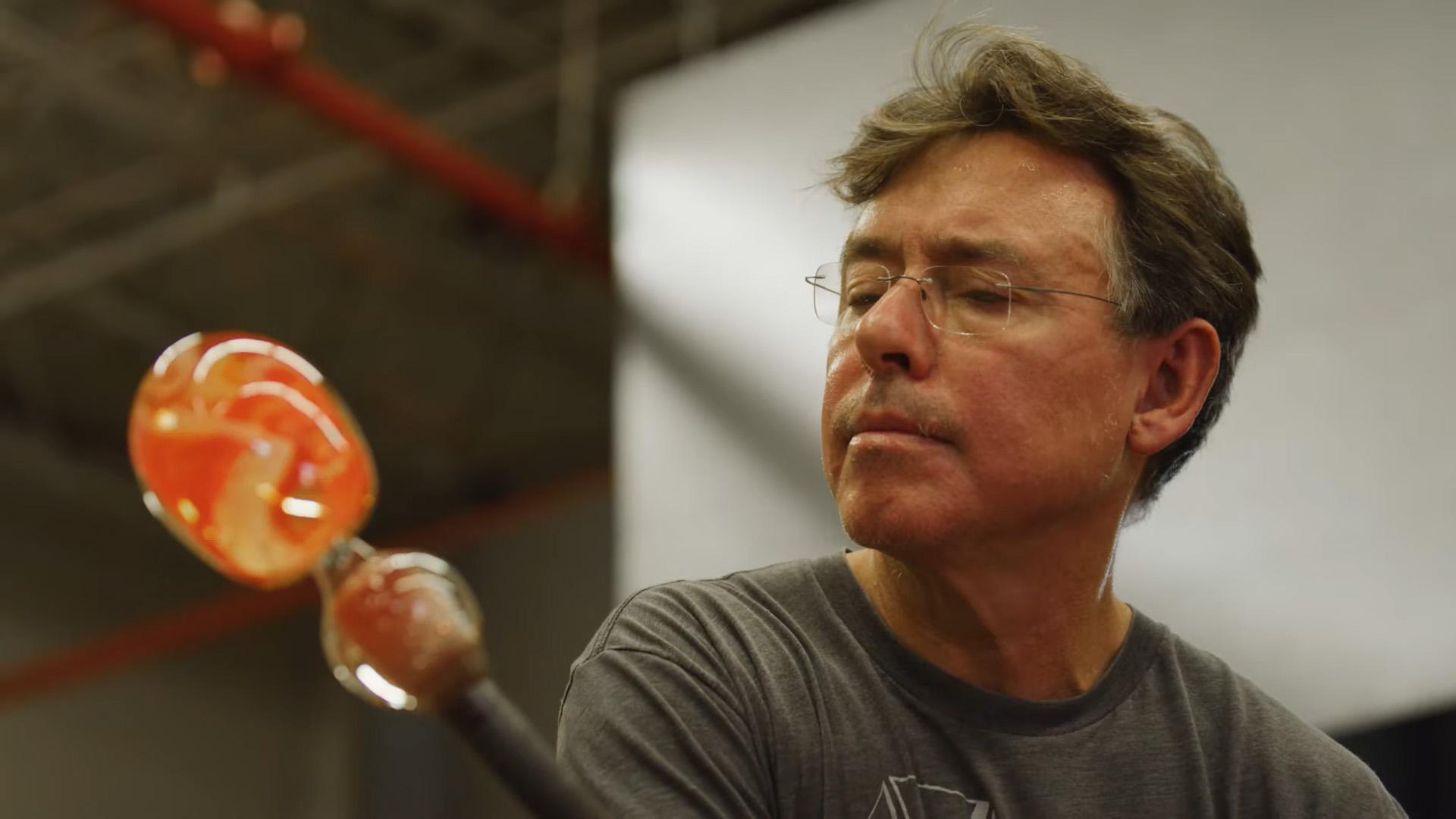 A man spins red hot glass on a rod.