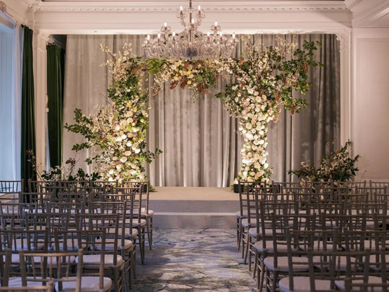 An extravagant floral wedding arch centered amongst rows of seating